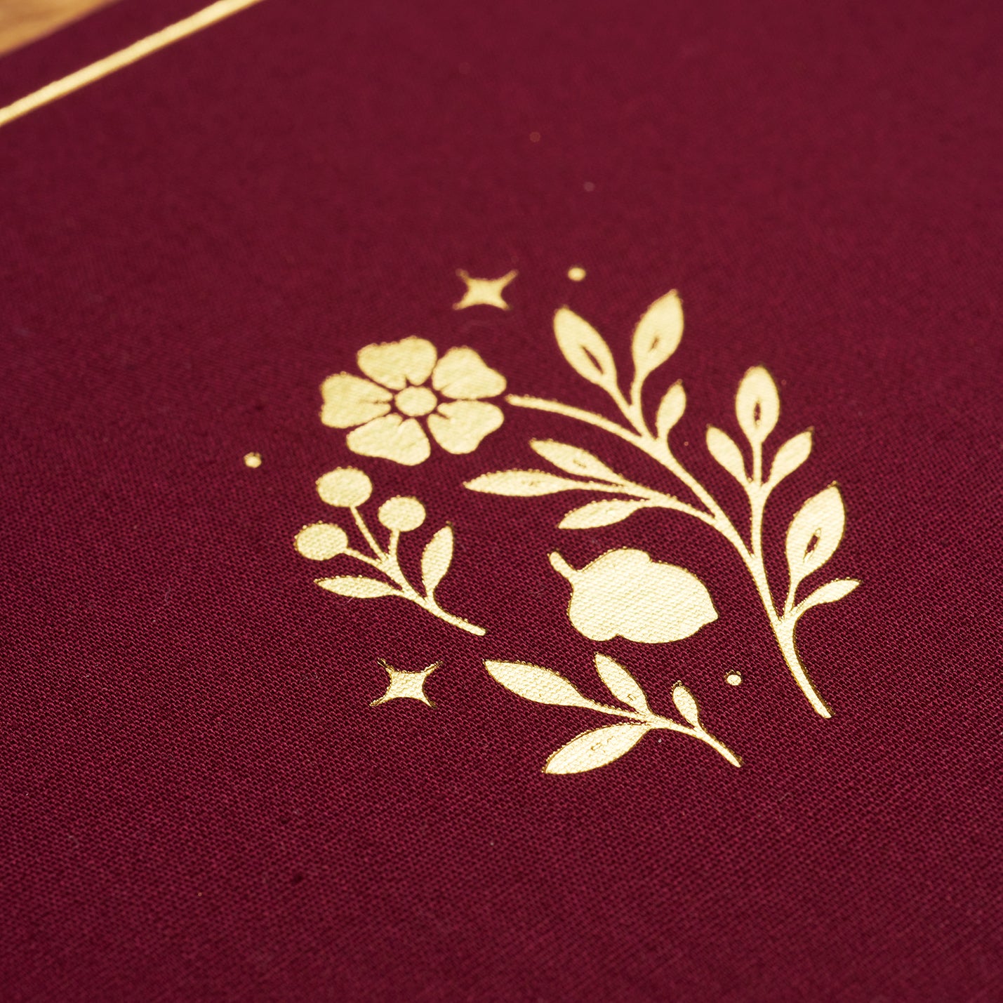 Detail shot of gold-foiled floral motif on plum linen cover.