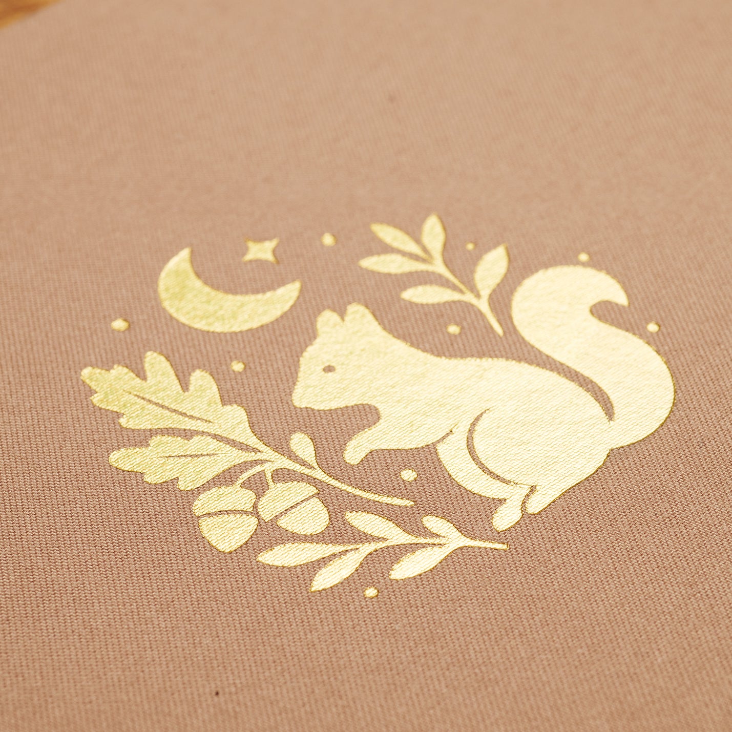 Gold foil design of a squirrel on a fawn fabric background