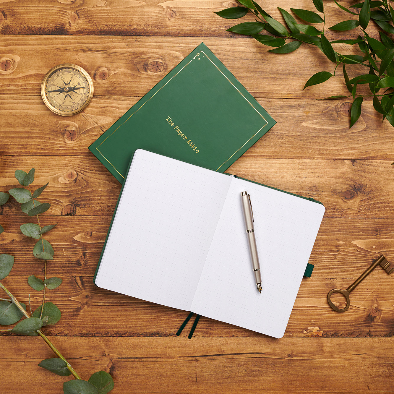 Open dotted journal beside its matching box on wooden desk showing lay-flat binding and soft dot-grid pages.