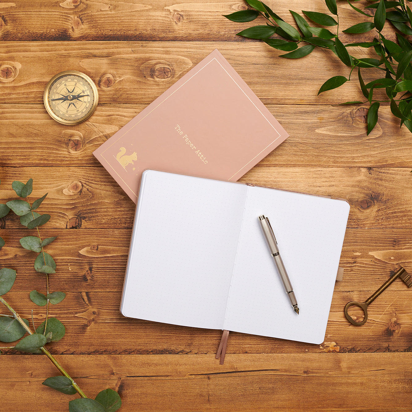 Open dotted journal beside its matching box on wooden desk showing lay-flat binding and soft dot-grid pages.